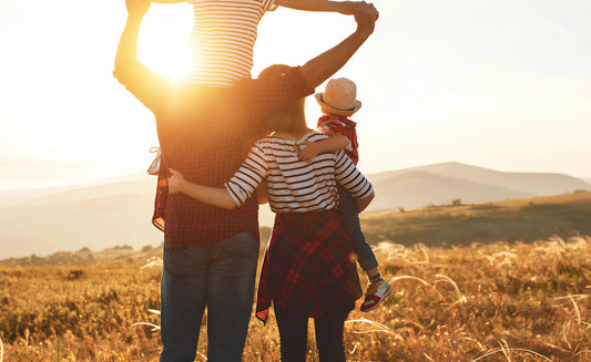 Des parents et leurs enfants admirant le coucher de soleil dans un champ