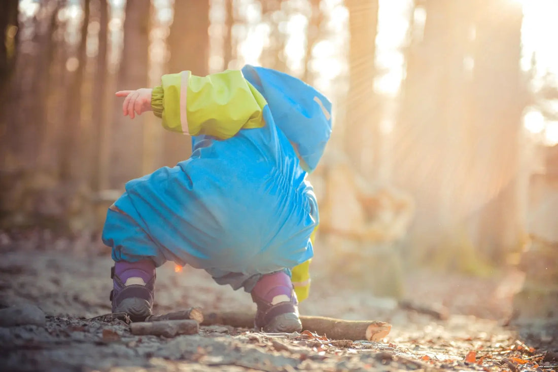 Un jeune enfant habillé de bleu, accroupi la forêt.