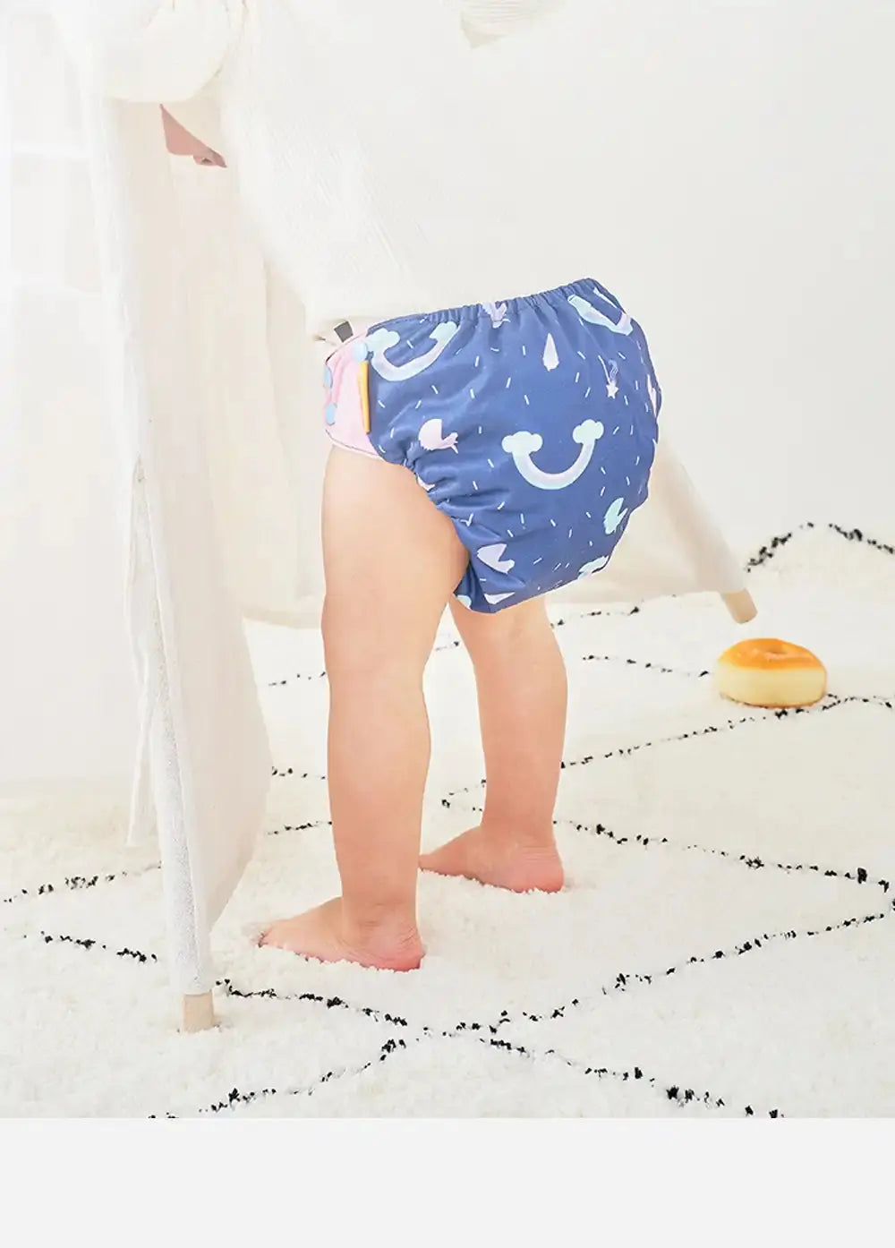 Enfant debout sur tapis blanc portant couche bleu